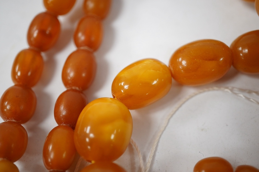 A single strand graduated oval amber bead necklace (a.f.), 90cm, gross weight 72 grams and three odd beads and an earring. Condition - poor